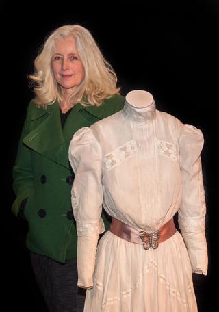 Actor Anne Louise Lambert standing next to a mannequin with the white lace dress costume she wore when filming Picnic at Hanging Rock 40 years earlier