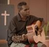 Portrait of Gurrumul playing guitar