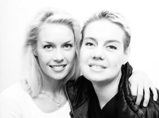 Black and white head and shoulders shot of two young women looking directly at camera.