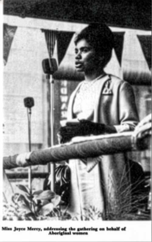 Joyce Mercy stands at a microphone addressing a National Aboriginal Day celebration in 1964
