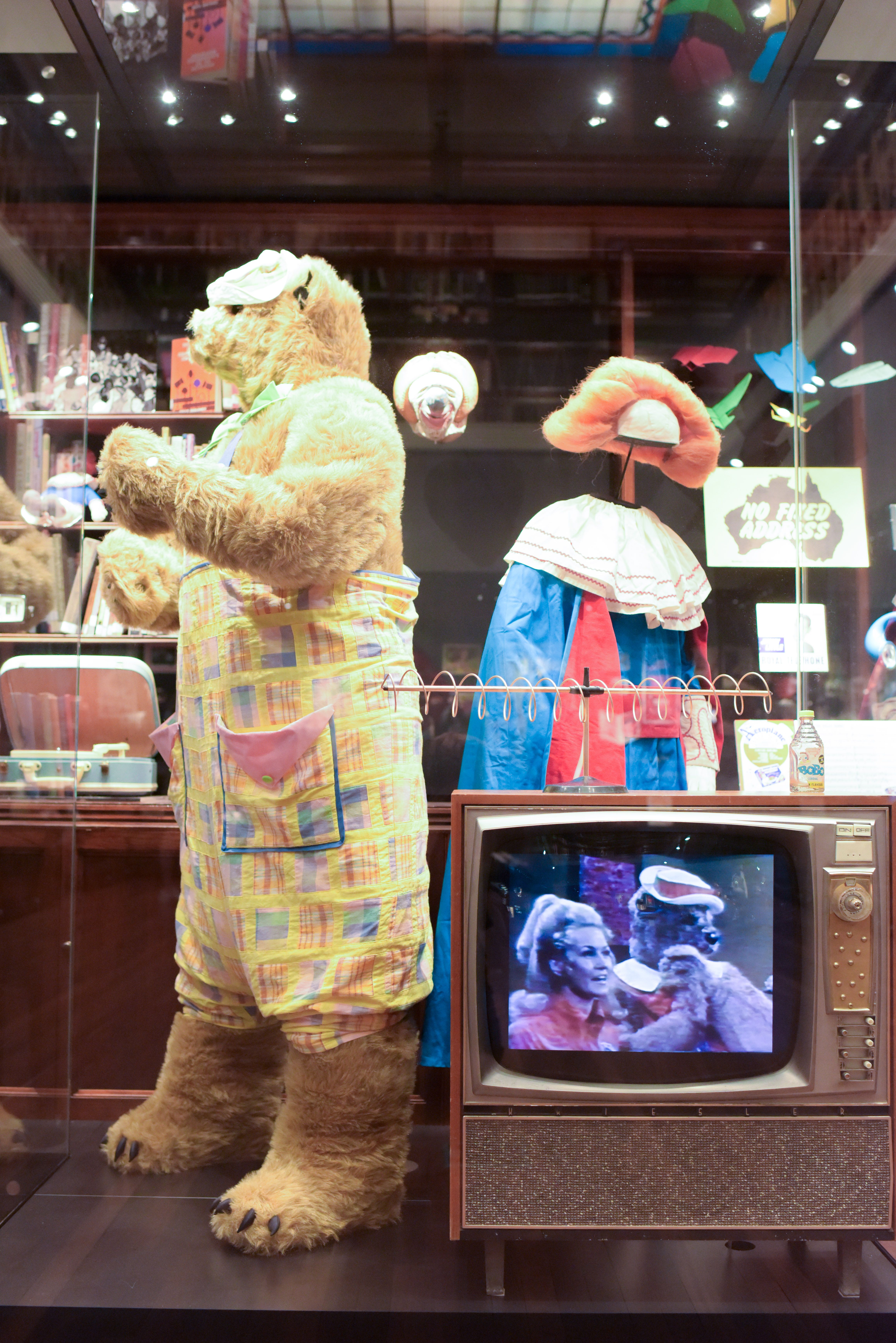 Fredd Bear costume on display in a glass case at the NFSA. A clip of Fredd Bear plays on a TV in front of the case