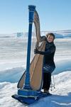 Photo of Alice Giles at Mawson Station, Antarctica playing a harp on the ice