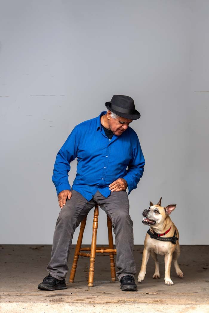 Richard Bell seated on a stool looking down at his dog Tilly, a Staffordshire cross.