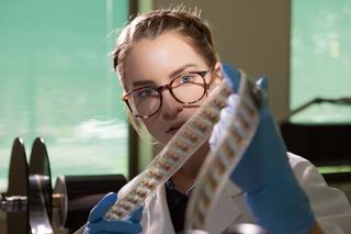 Young woman inspecting a strip of film.