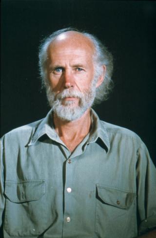 Filmmaker Ian Dunlop looks at the camera. He is in a studio with a black background.