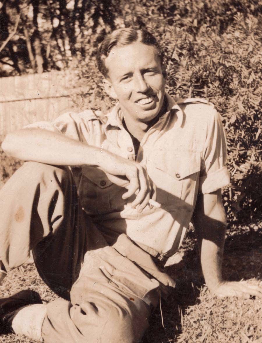 Composer James Joseph White seated on the grass and smoking a cigarette