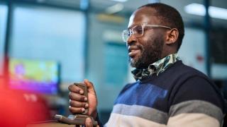 A seated man holding a video gaming joystick.