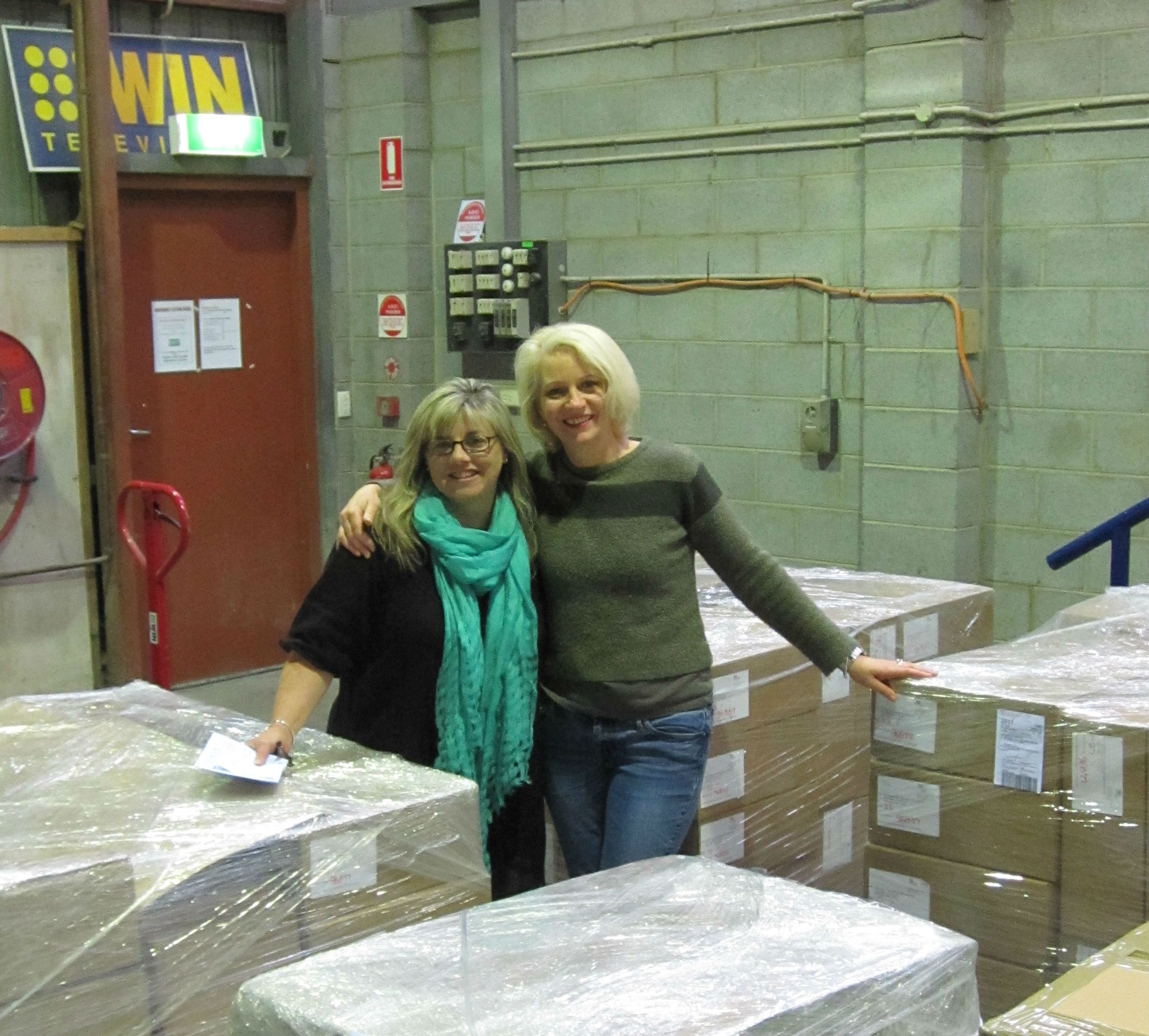 Two NFSA staff members embracing in a room filled with boxes on pallets.