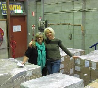 Two NFSA staff members embracing in a room filled with boxes on pallets.