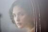 Rose Byrne as Iris in The Tender Hook, looks out a window that is fogged over and covered in raindrops.