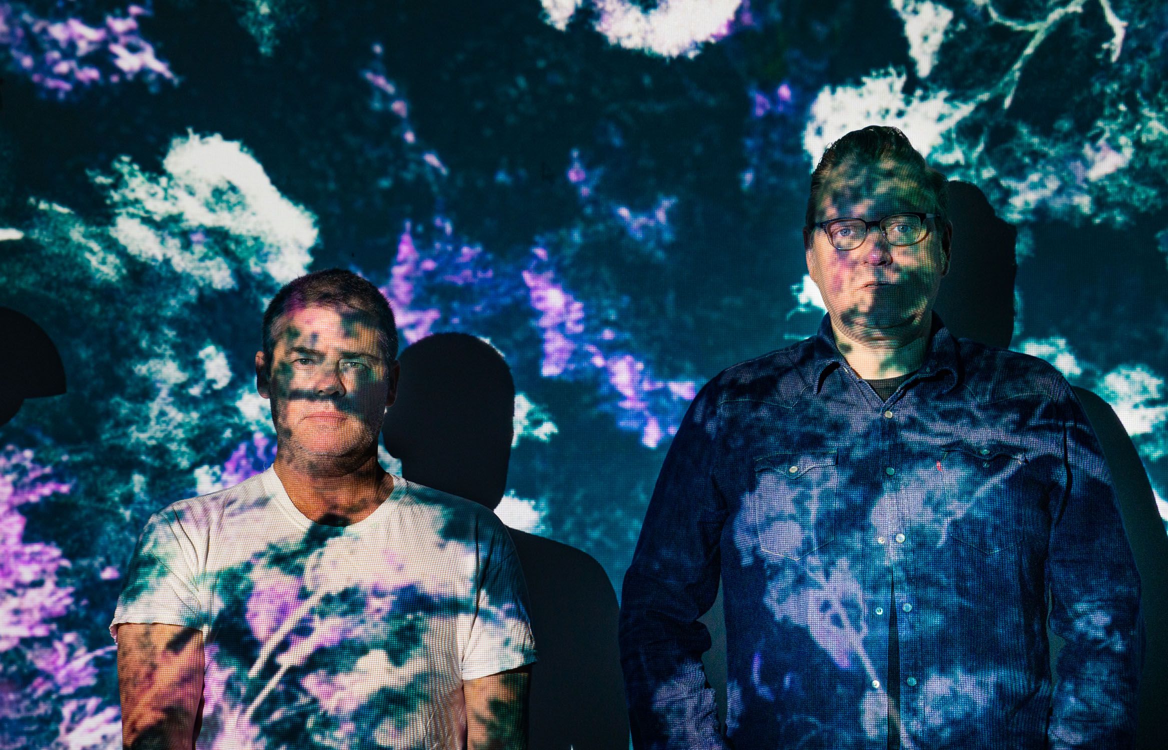 Gary Sinclair and James McGrath standing against a screen with colourful images projected onto them