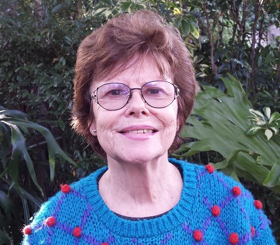Head and shoulders portrait photo of Lesley Cansdell against a lush garden
