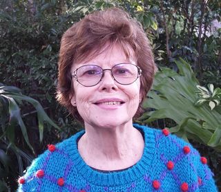Head and shoulders portrait photo of Lesley Cansdell against a lush garden