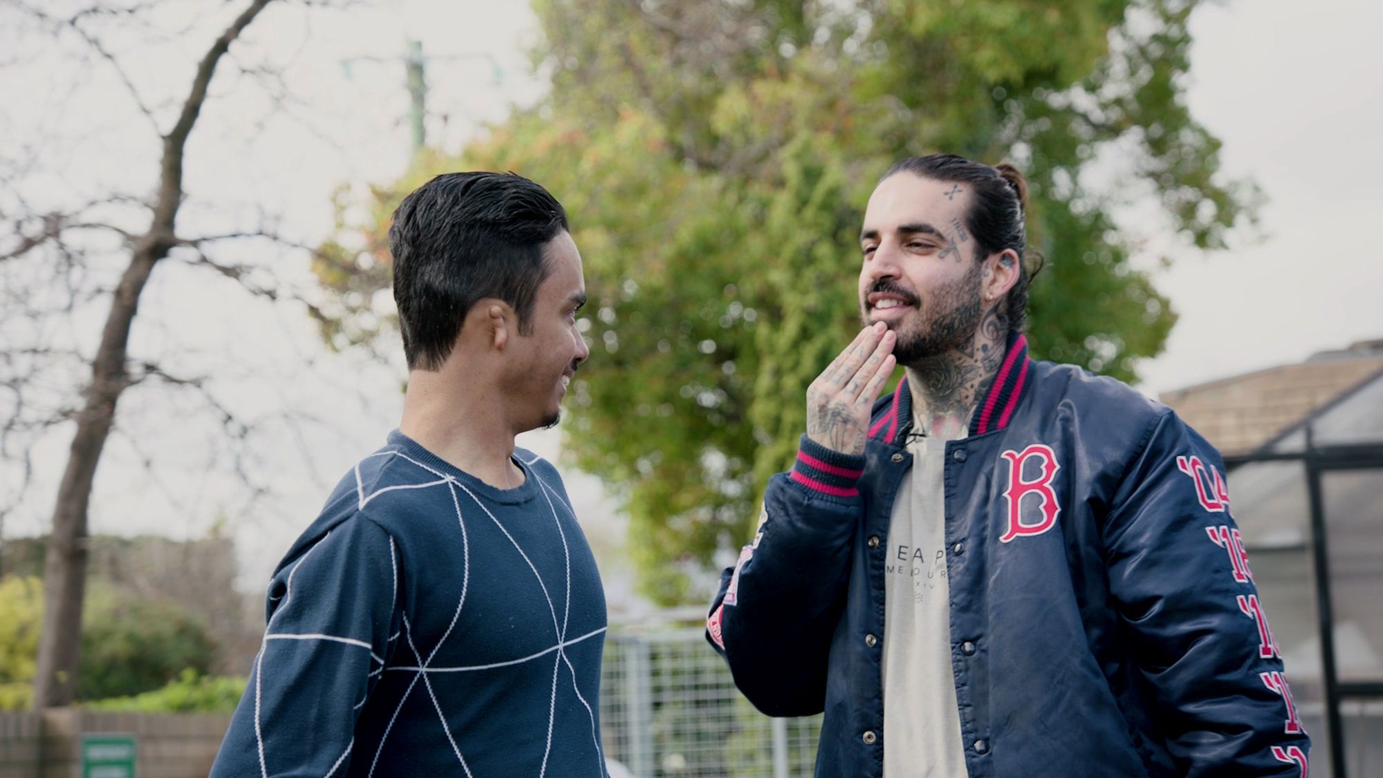 Two men stand outside speaking in sign language.