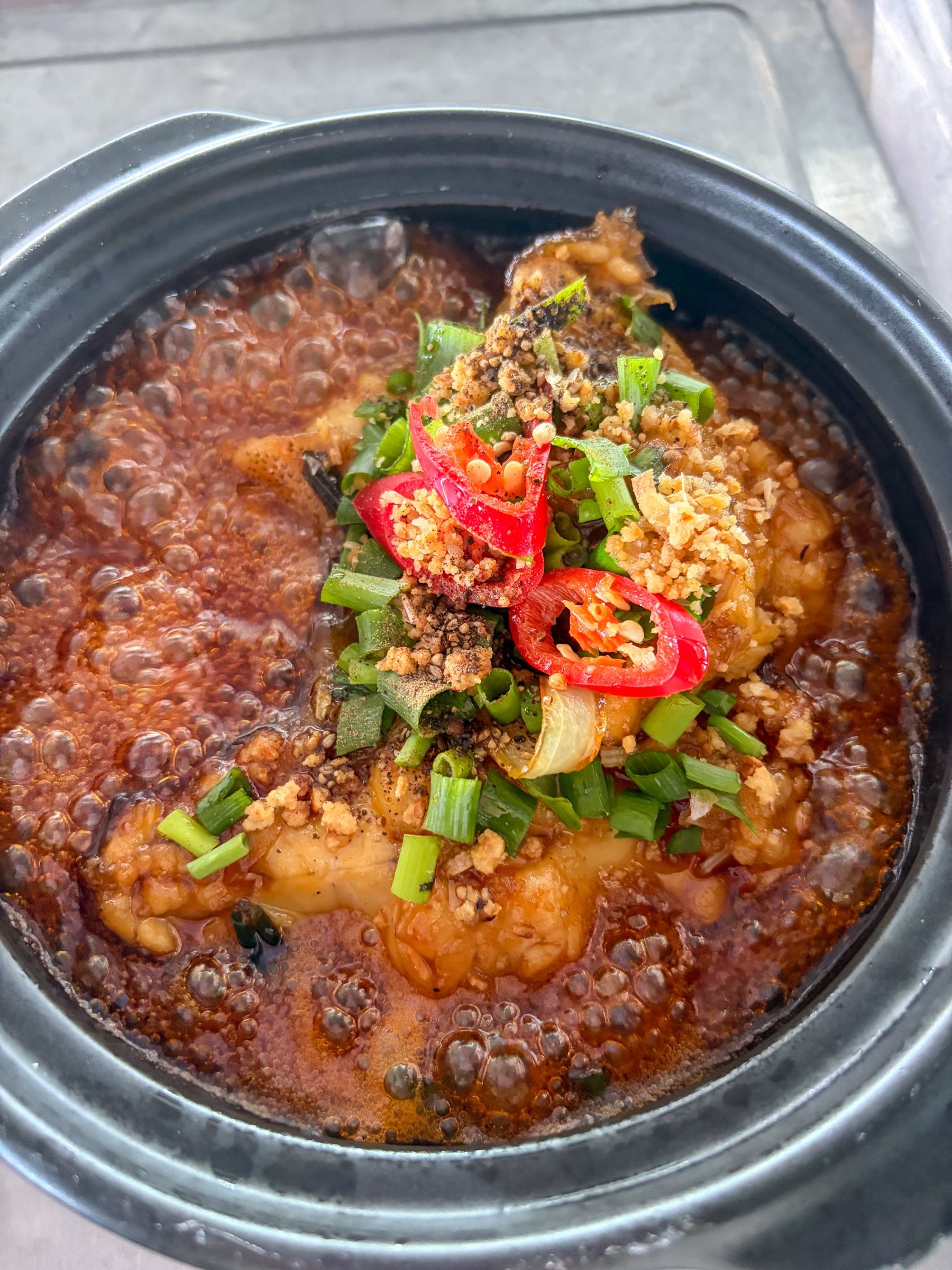 Cá kho tộ sốt sánh trong nồi đất, rắc hành lá và ớt