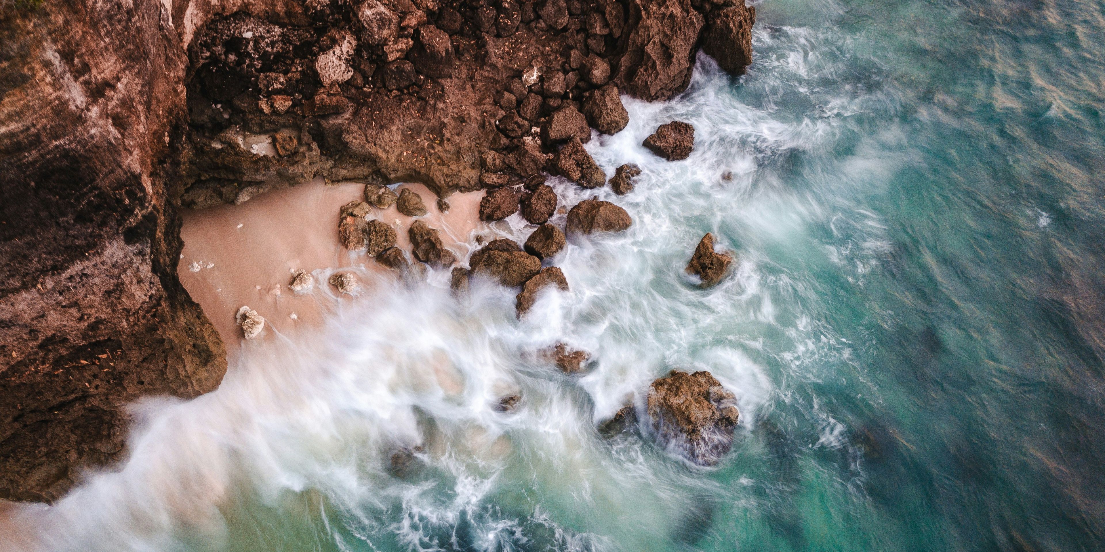 an aerial view of waves crashing against a rocky shoreline .