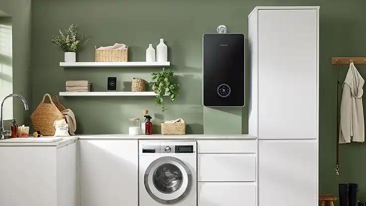 Black boiler in a utility room above a washing machine
