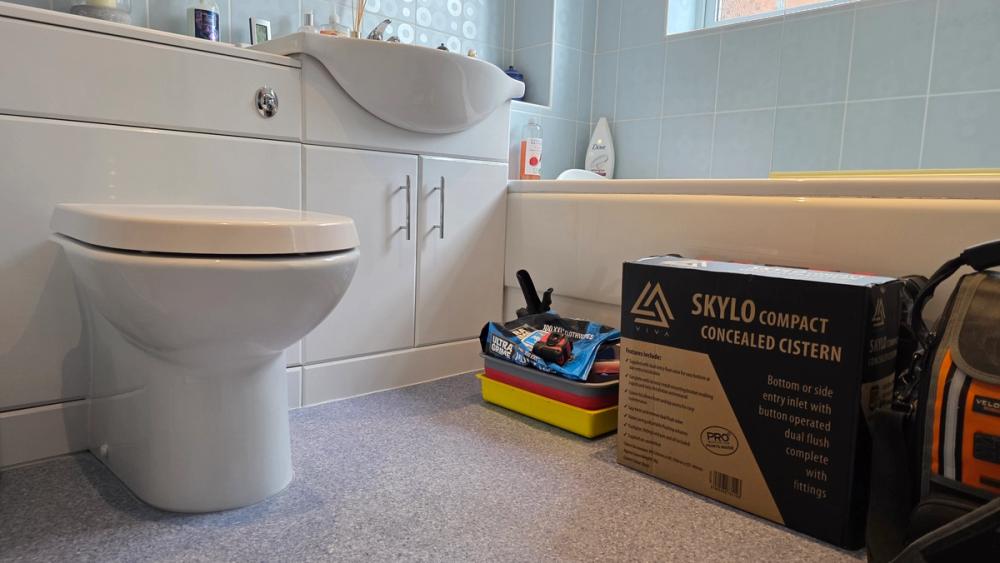 Toilet beside the new concealed cistern in its box, ready to be fitted