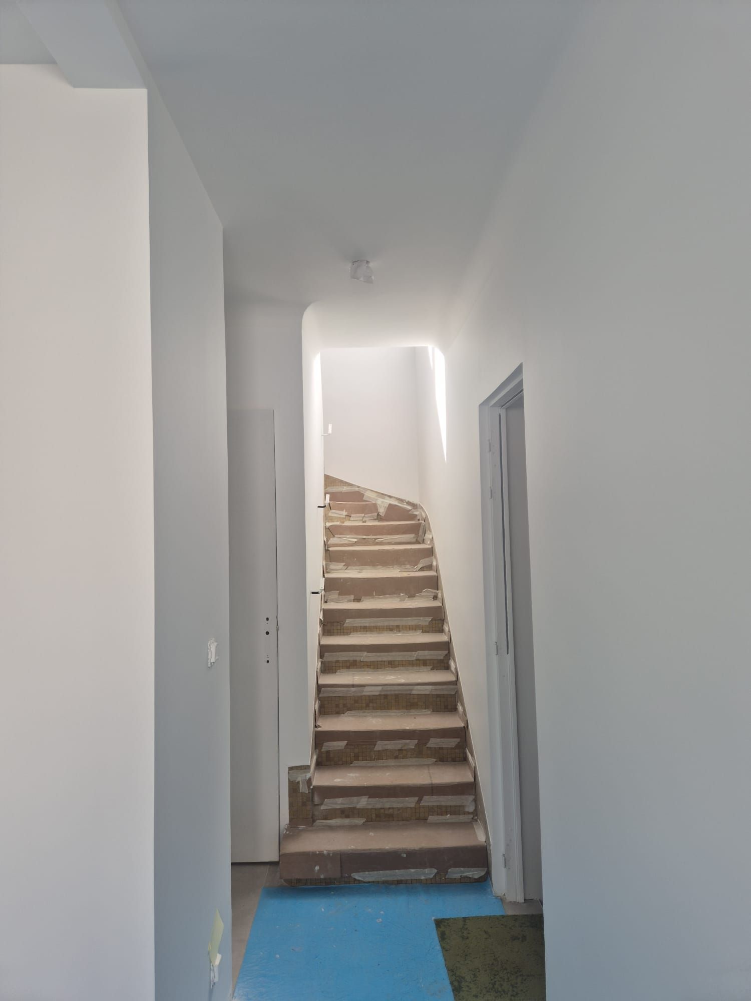 Couloir blanc menant à un escalier, marches protégées