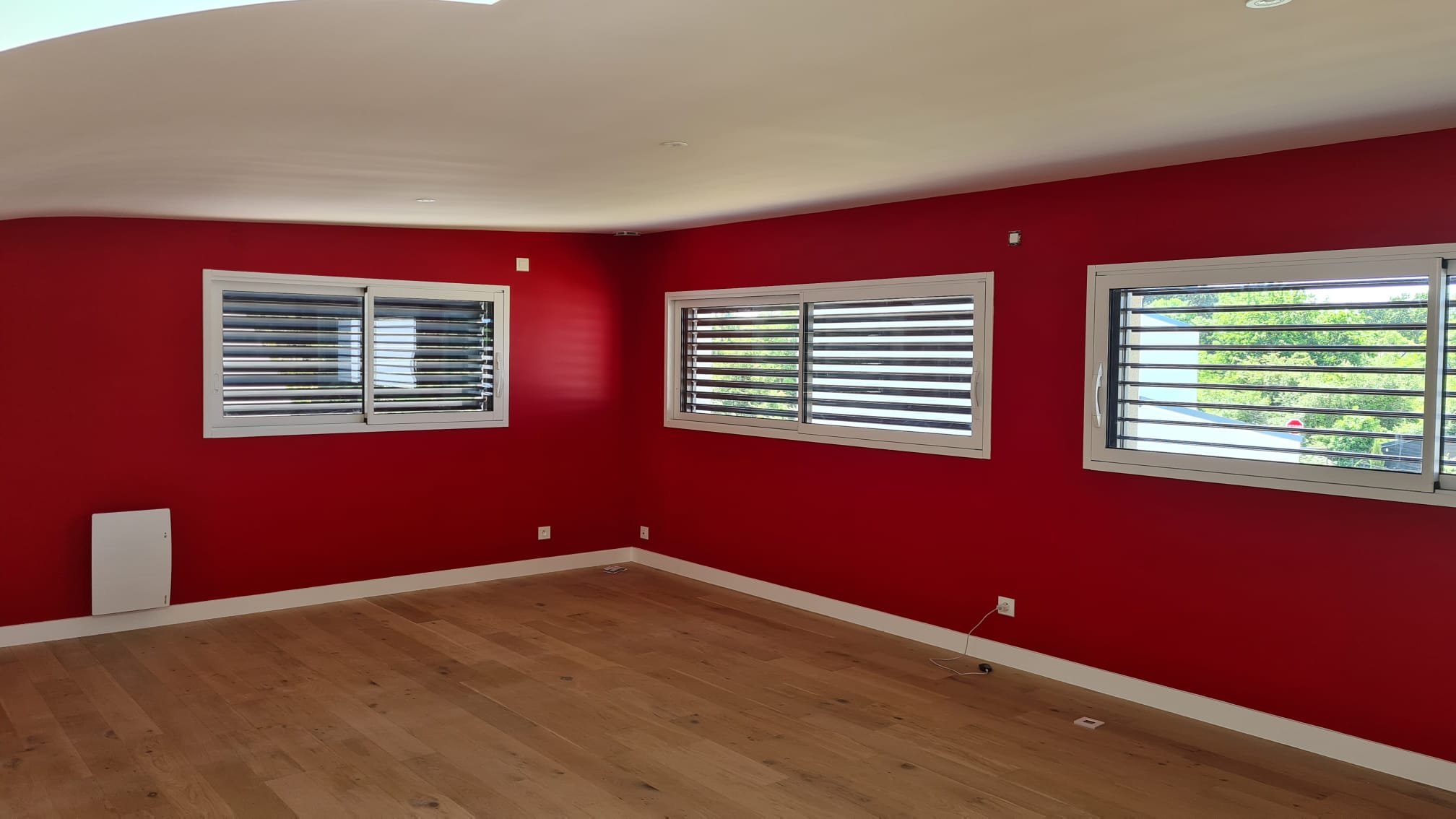 Séjour d’une maison contemporaine, mur d’accent rouge profond et parquet chêne