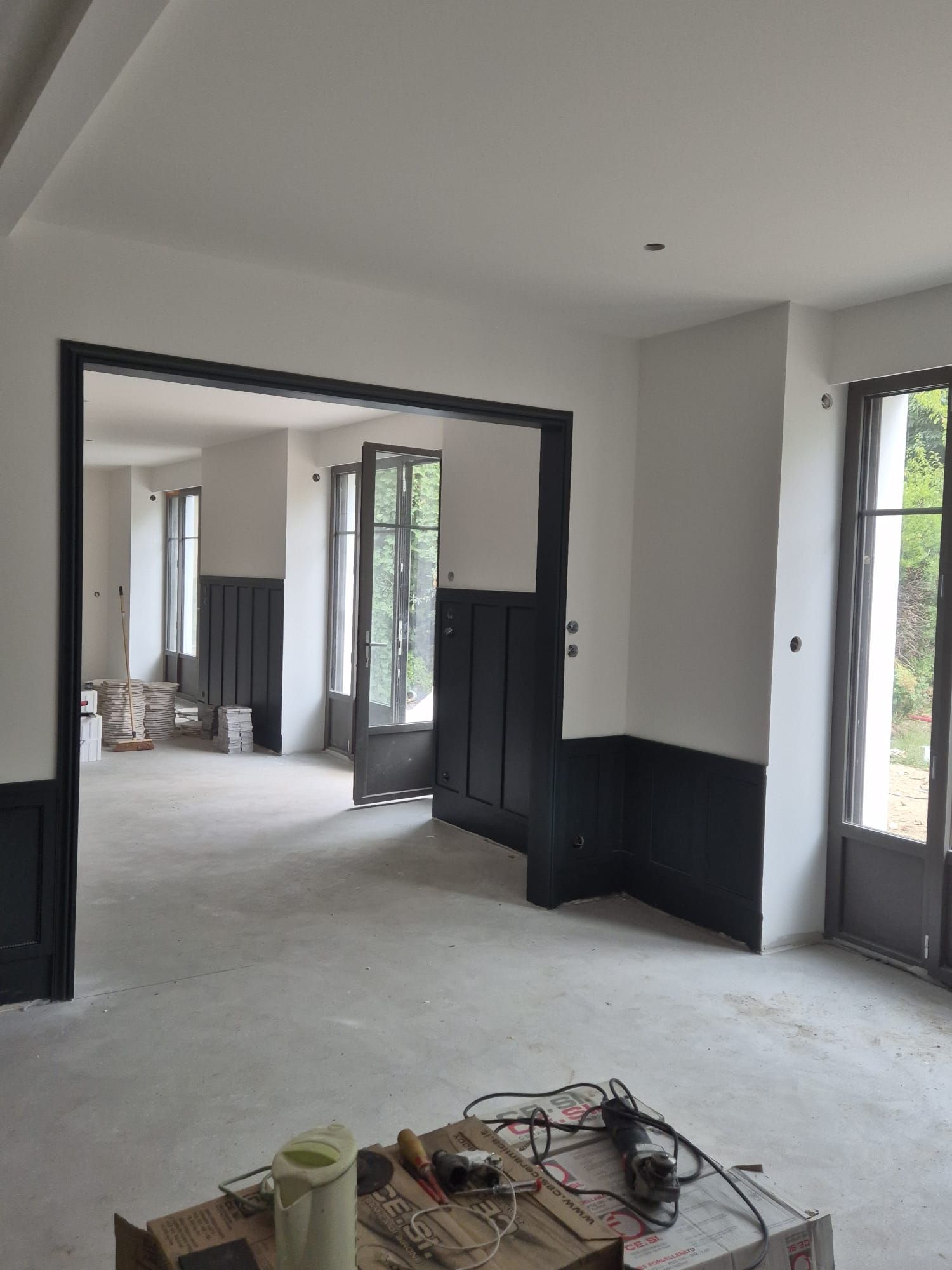 Entrée d’une maison avec encadrements laqués anthracite et enfilade de pièces