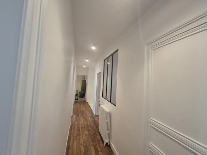 Couloir d’appartement aux lambris blancs et parquet clair