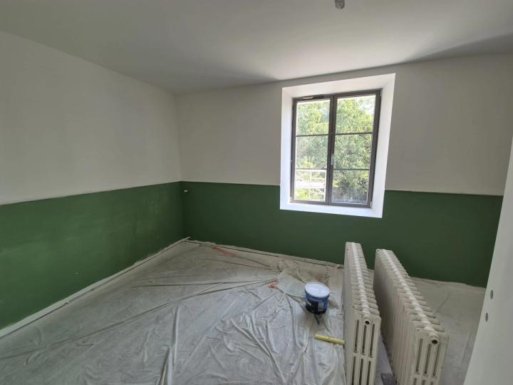 Chambre au soubassement vert peint à hauteur d’appui, radiateur en fonte