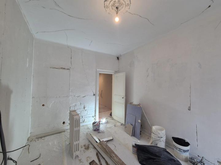 Pièce avant travaux, murs décapés et plâtres fissurés