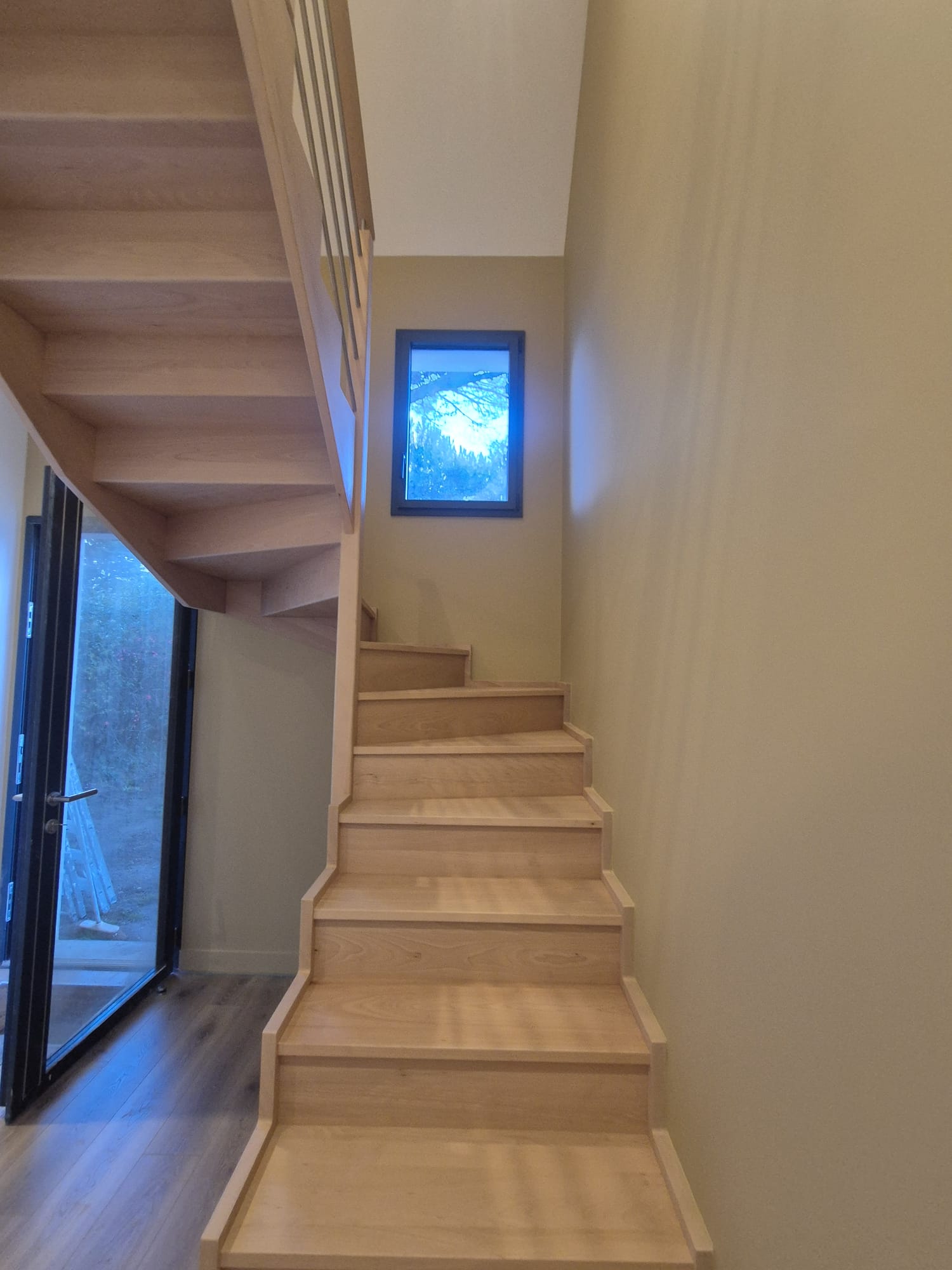 Escalier bois clair dans une circulation aux murs sable