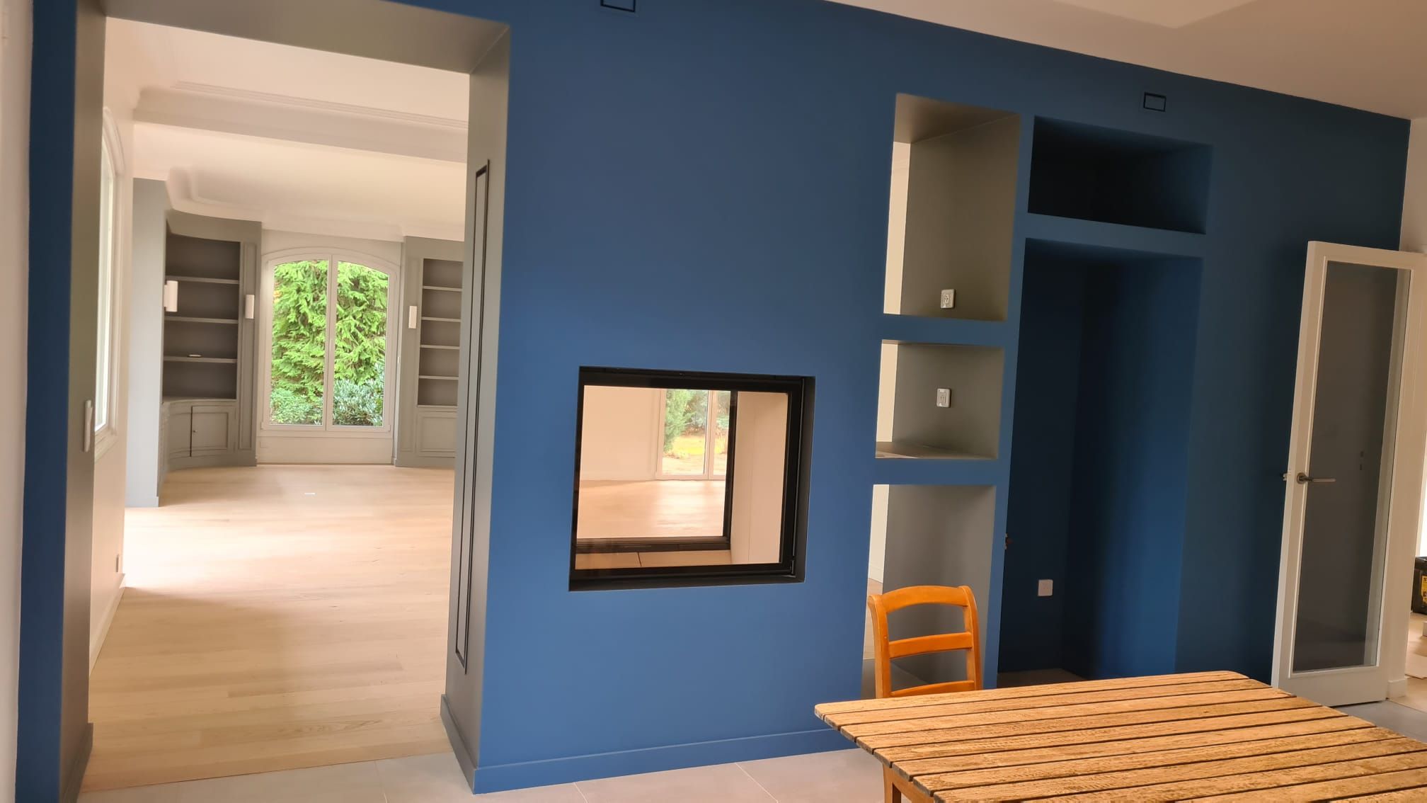 Séjour avec mur bleu ardoise, niches maçonnées et passe-plat