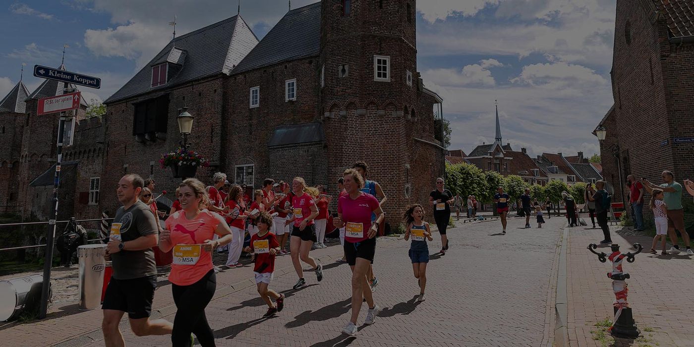 Groep hardlopers bij een historische stadspoort