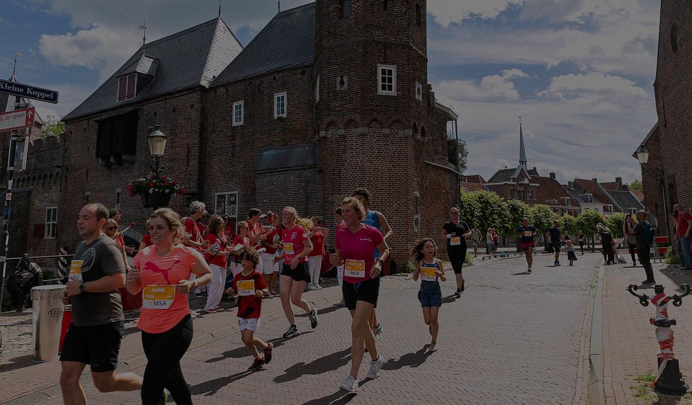 Groep hardlopers bij een historische stadspoort