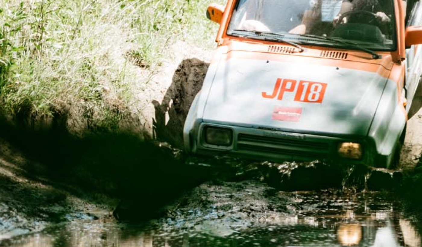 Offroad-voertuig ploegt door een modderige waterplas in het bos