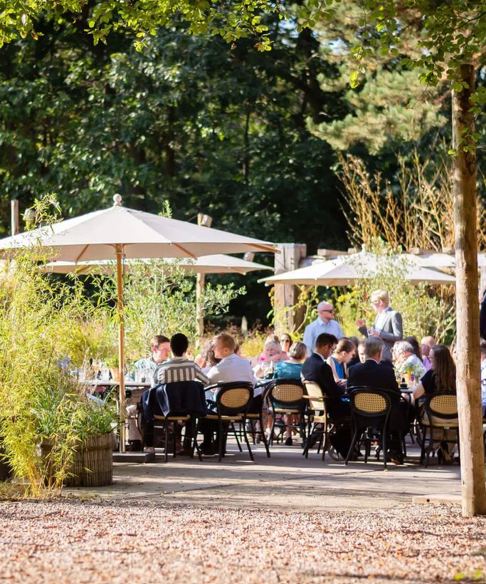 Gasten aan tafels op een groen terras