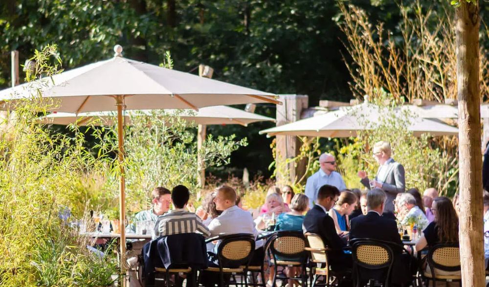 Gasten aan tafels op een groen terras