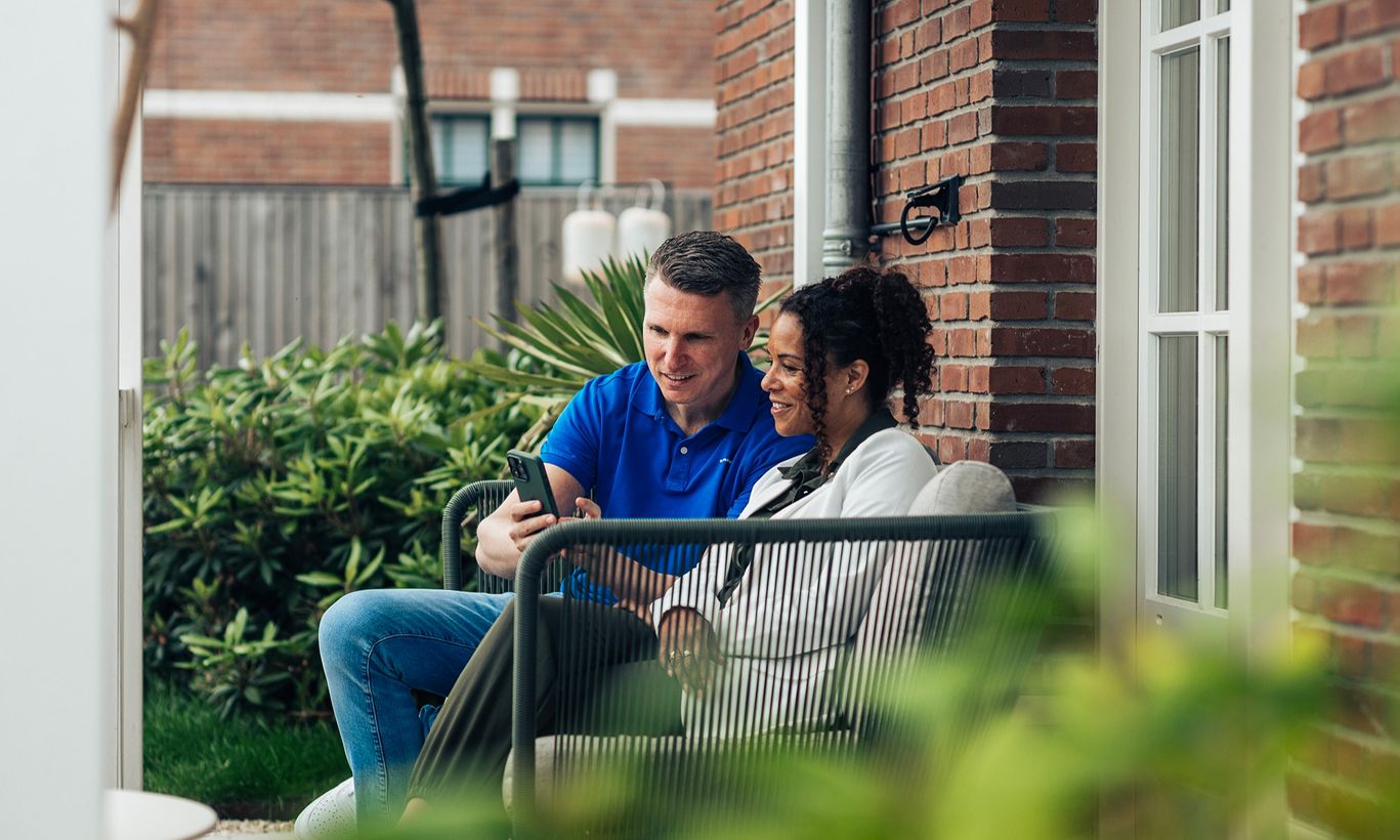 Drie mensen in gesprek bij een woning