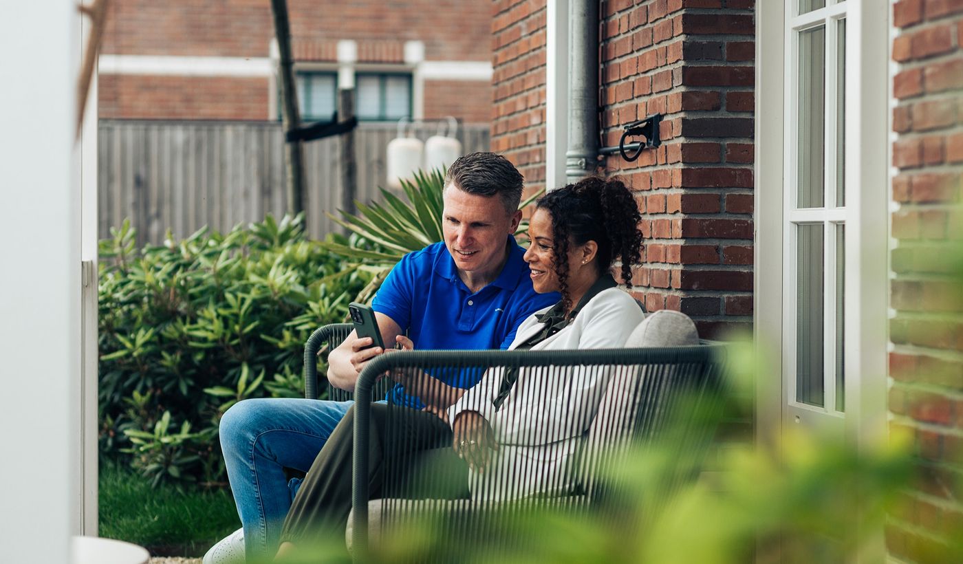 Drie mensen in gesprek bij een woning