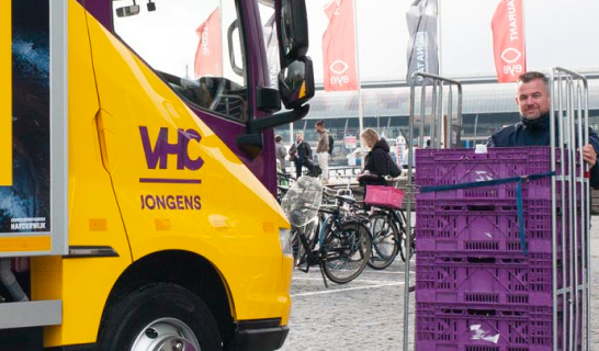 VHC-vrachtwagen naast stapels kratten