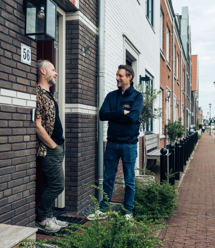 Twee mensen in gesprek voor een rijtjeshuis