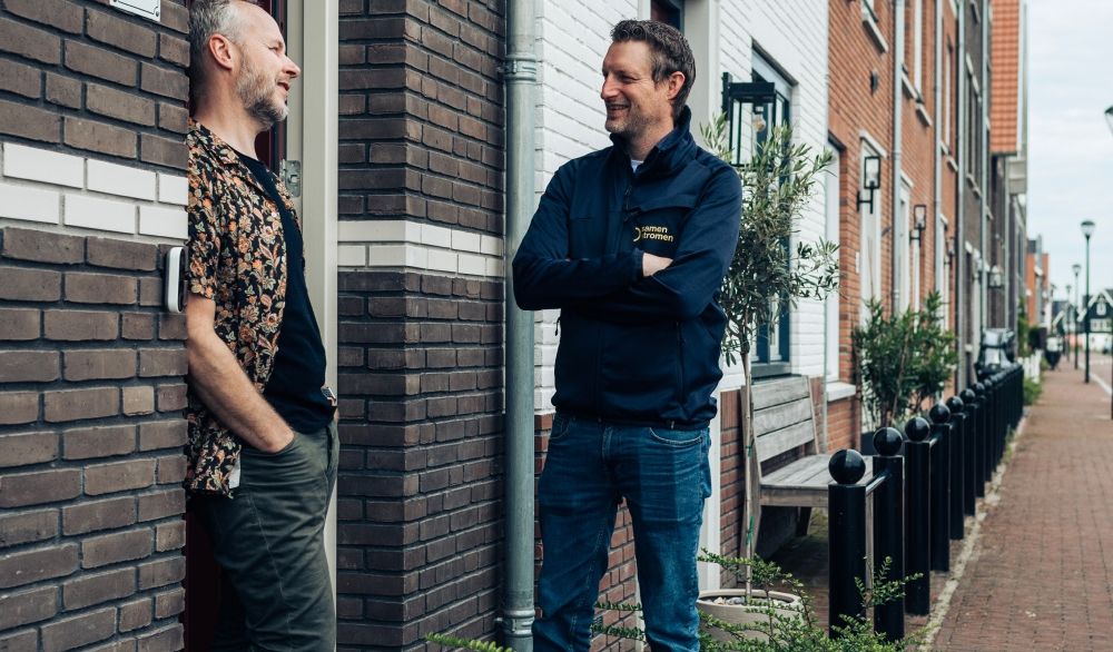 Twee mensen in gesprek voor een rijtjeshuis
