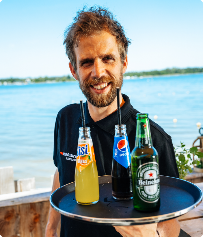 Lachende medewerker serveert drankjes op een dienblad aan het water