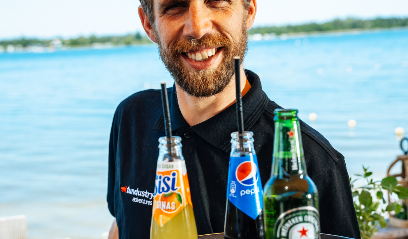 Lachende medewerker serveert drankjes op een dienblad aan het water
