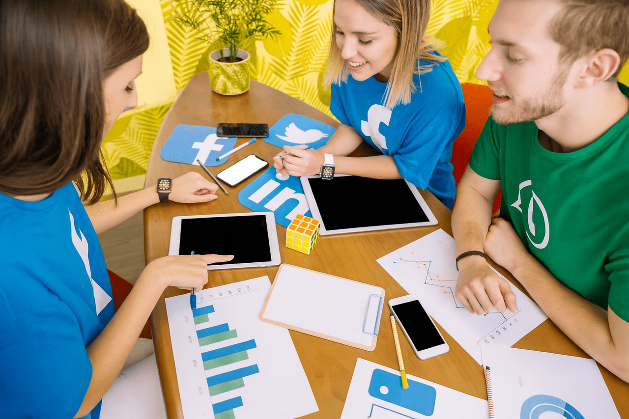 Zespół planujący kampanię przy stole z tabletami, wykresami i smartfonami