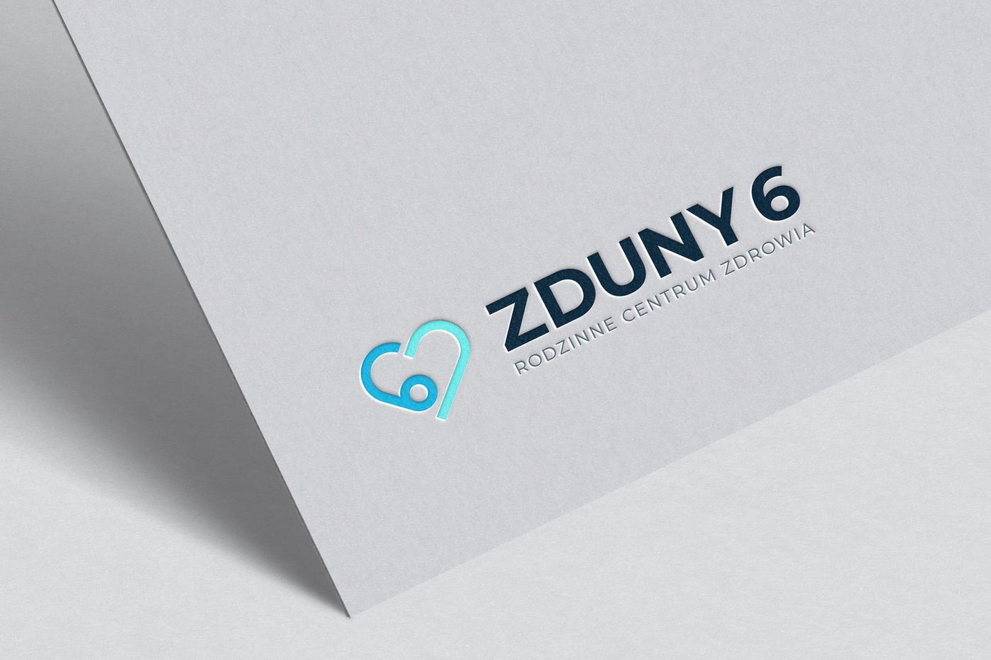 Logo Zduny 6 wytłoczone na papierowej wizytówce — serce z cyfrą 6 w kolorze turkusowym