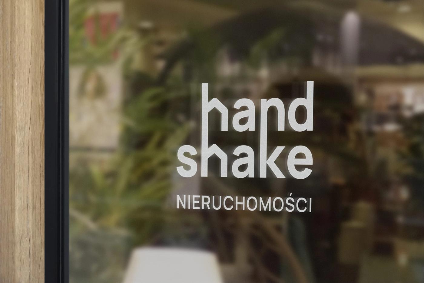 Logo Handshake wytrawione na szklanych drzwiach biura agencji nieruchomości