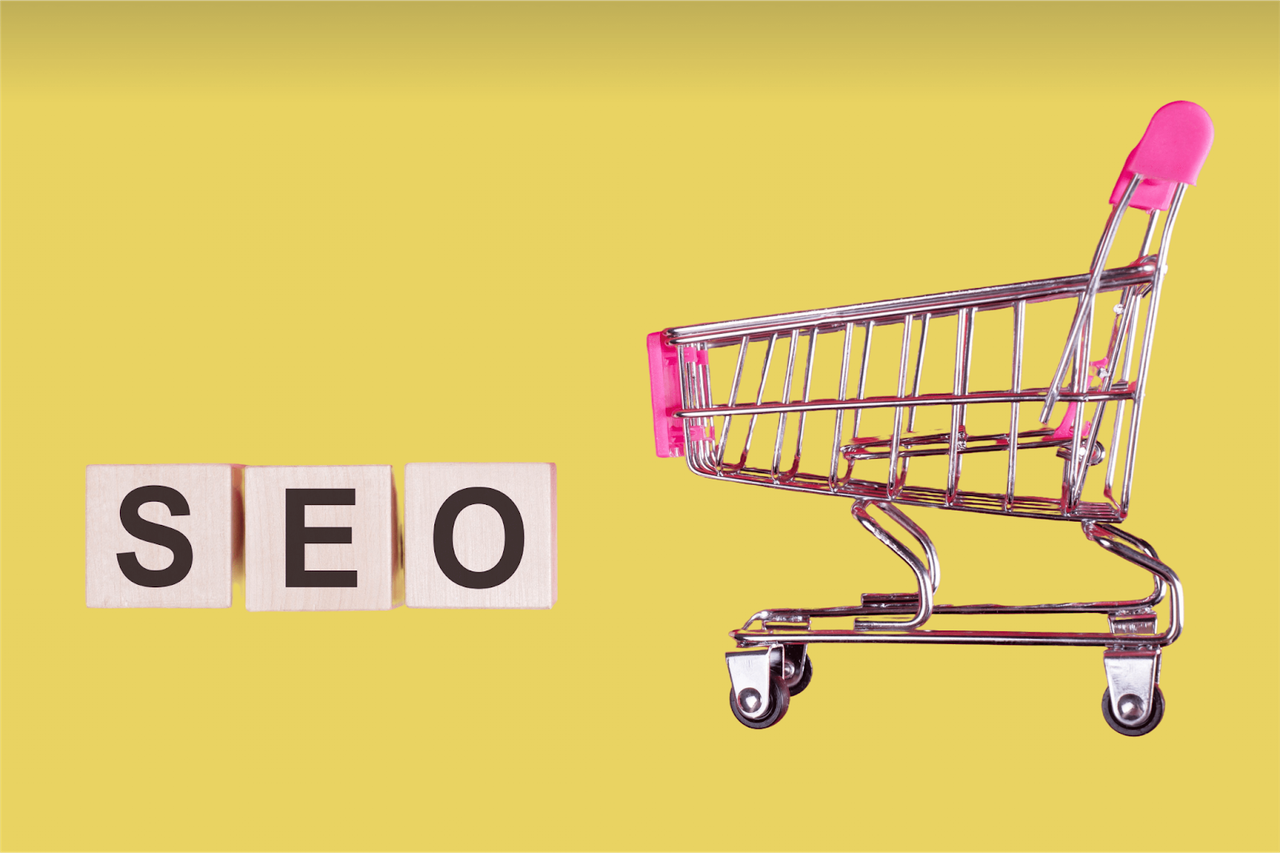 Drewniane klocki z literami SEO obok wózka sklepowego na żółtym tle