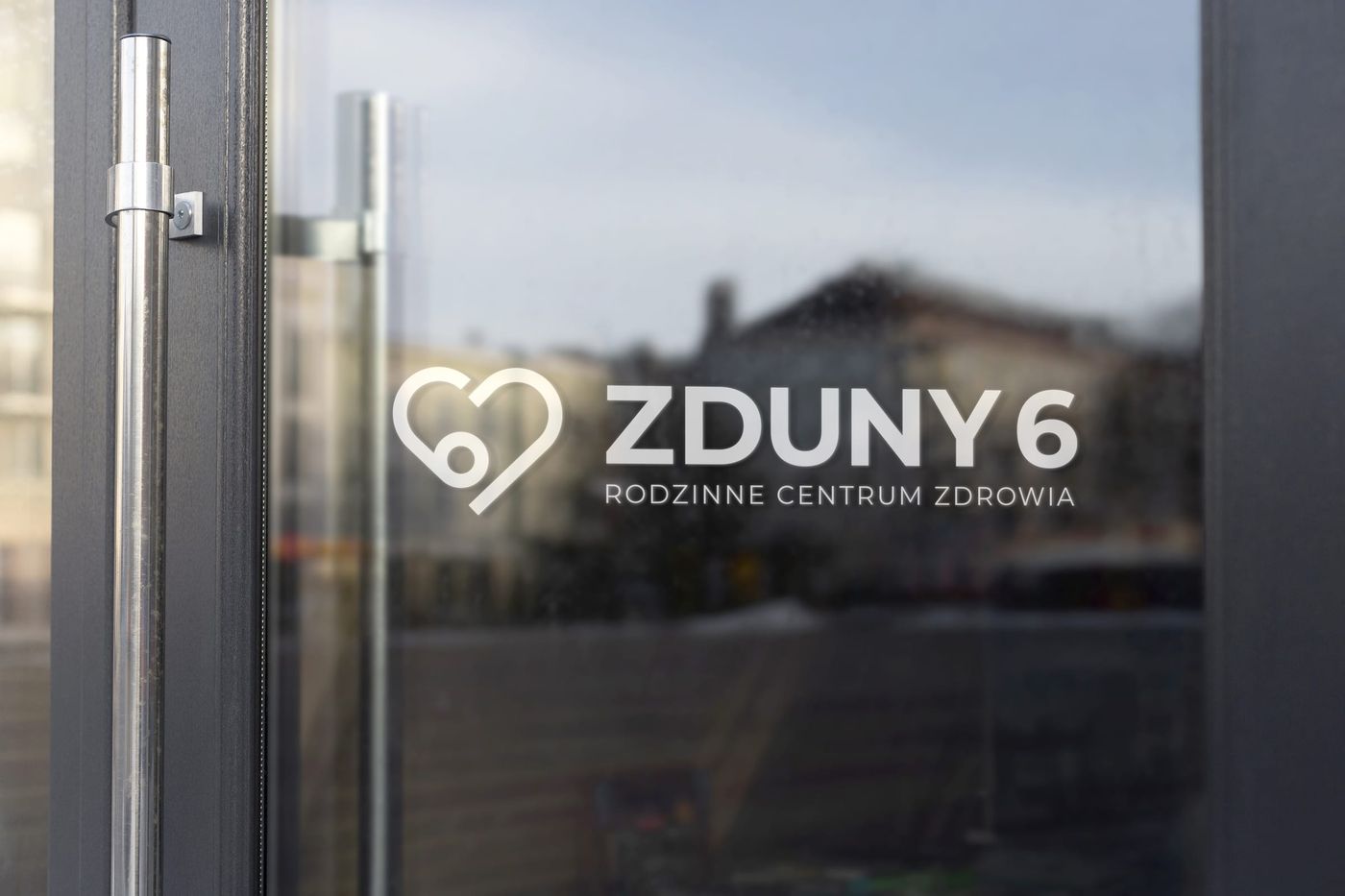 Szklane drzwi wejściowe Zduny 6 z białym nadrukiem logo Rodzinne Centrum Zdrowia