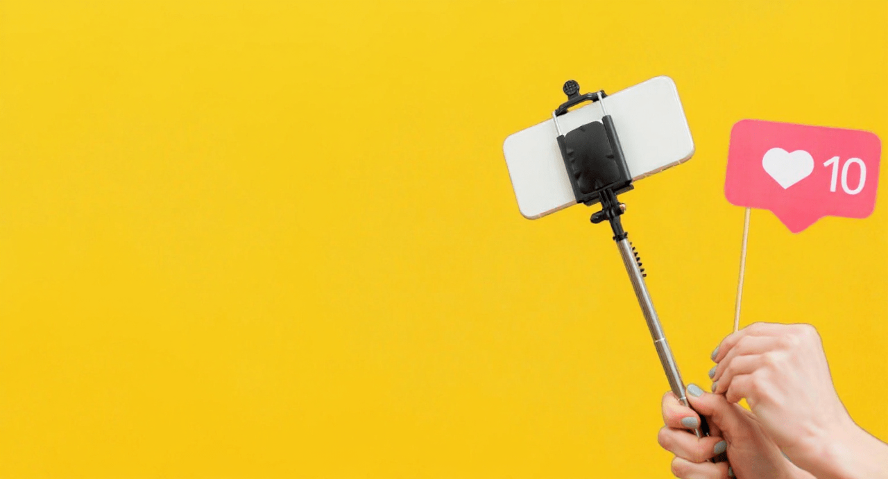 Ręka trzymająca selfie stick ze smartfonem i ikoną 10 polubień