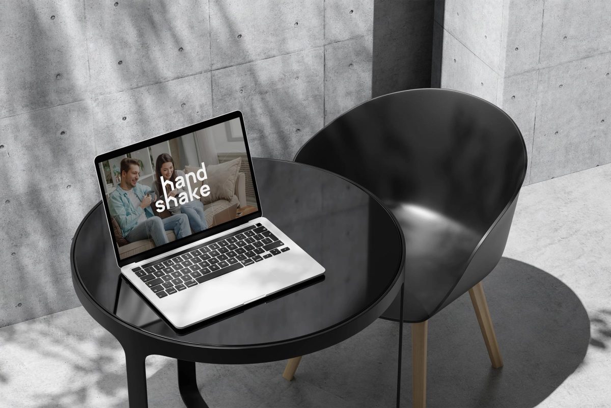 Laptop z otwartą stroną Handshake na minimalistycznym, czarnym stoliku