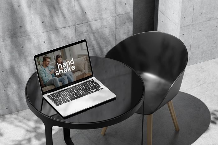 Laptop z otwartą stroną Handshake na minimalistycznym, czarnym stoliku